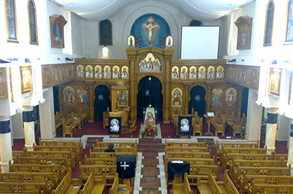 The interior of a Coptic Orthodox church: wooden iconostasis, icons, pews
